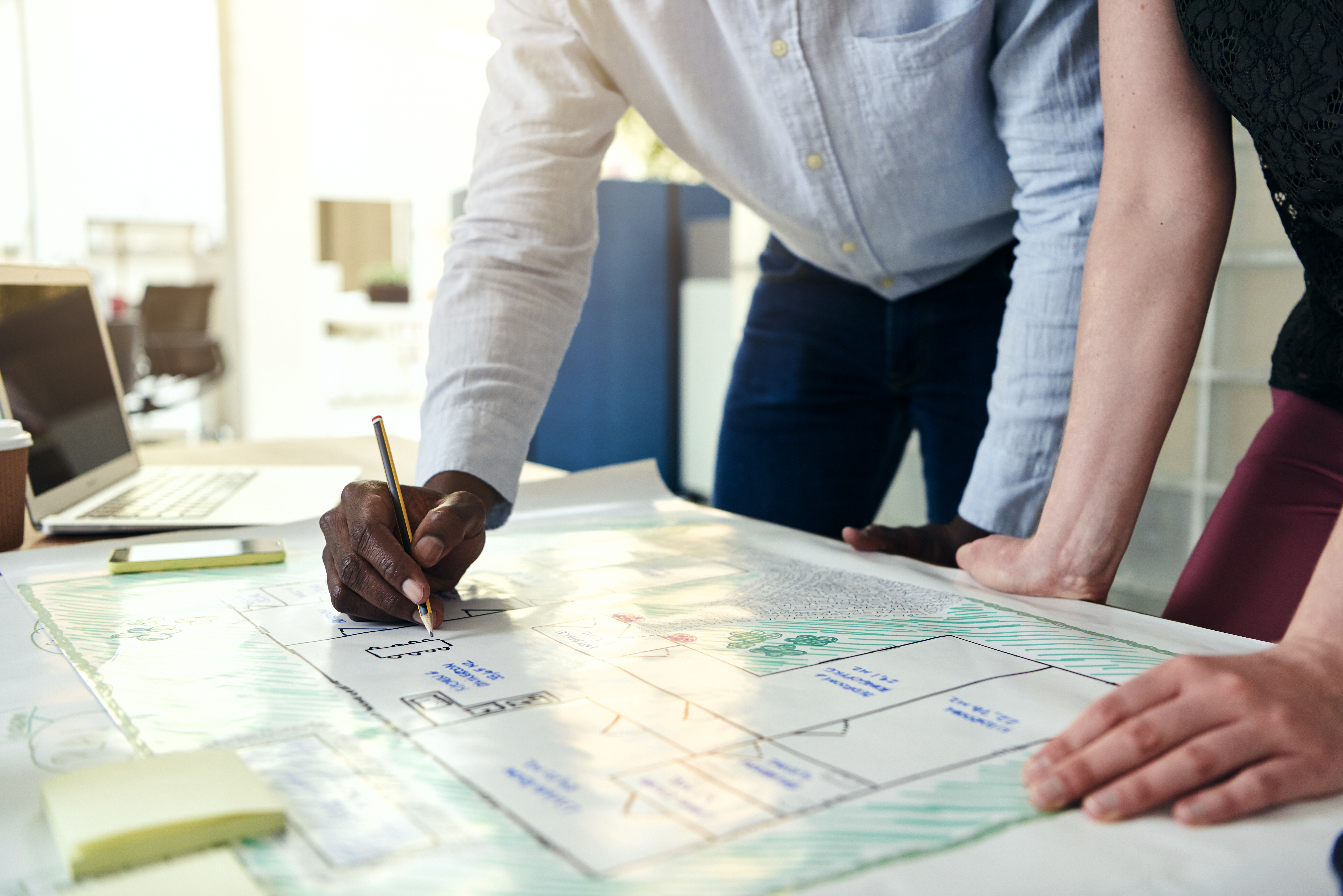 Estudio de viabilidad y planificación arquitectónica Diseñadores revisando planos de un edificio sobre una mesa de trabajo